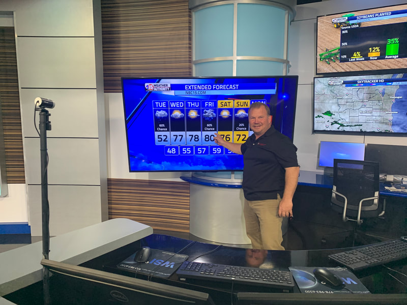 Founder Mike Foerster pointing to a weather forecast shown on TV | Madison waterproofing company